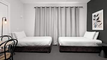 Una habitación de hotel moderna con dos camas individuales, un escritorio y una silla.