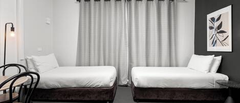 Una habitación de hotel moderna con dos camas individuales, un escritorio y una silla.