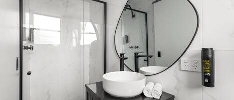 A bathroom with a large mirror, a round sink, and a black vanity.