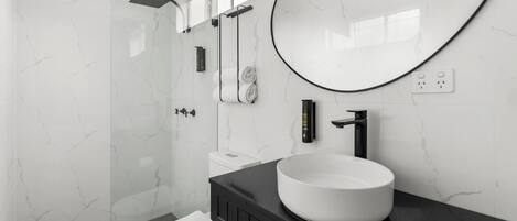 A modern bathroom with a white marble sink, black vanity, and a large mirror.