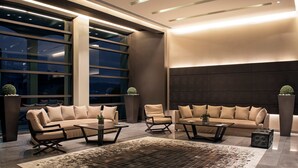 A modern living room with a large sofa set, coffee tables, and decorative plants. - Esperos Palace Luxury & Spa Hotel (Kastoria)