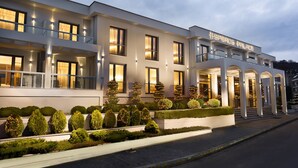 A modern hotel with a symmetrical facade, multiple balconies, and well-lit windows. - Esperos Palace Luxury & Spa Hotel (Kastoria)