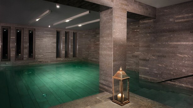 A spa area with a pool, stone walls, and a lantern. - Esperos Palace Luxury & Spa Hotel (Kastoria)