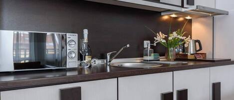 A modern kitchen with a built-in microwave, a coffee maker, and a vase with flowers on the counter.