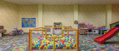 A play area with a ball pit, a slide, and a map on the wall.
