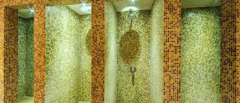Un baño con tres cabinas de ducha, cada una con un muro de mosaico cerámico y un cabezal de ducha.
