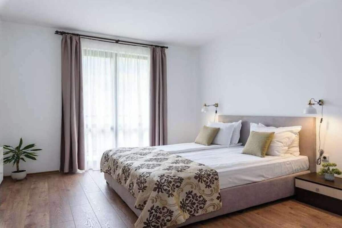 Ett modernt hotellrum med en stor säng, sänglampor, ett nattduksbord och en krukväxt.