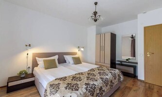 Un dormitorio con una cama doble, mesitas de noche, un armario, un espejo y una araña.