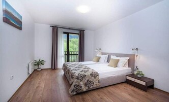 Un dormitorio con una cama, una mesita de noche, una planta en maceta y una ventana con cortinas.