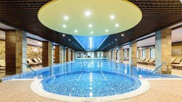 Una piscina techada, sillones reclinables de piscina