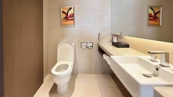A modern bathroom with a toilet, a sink, and a mirror. There are two framed artworks on the wall.