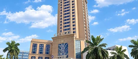 A multi-story hotel with a prominent entrance and a tall building in the background.
