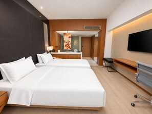 A hotel room with two beds, a desk, a chair, a TV, and a bathroom visible in the background. - Grand Mercure Dongguan Humen (Dongguan)