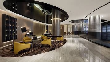A modern lobby with a curved ceiling, a central column, and seating areas.
