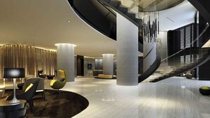 Un hall d’entrée moderne avec un escalier à volutes, des espaces de détente et une grande structure en forme de colonne.