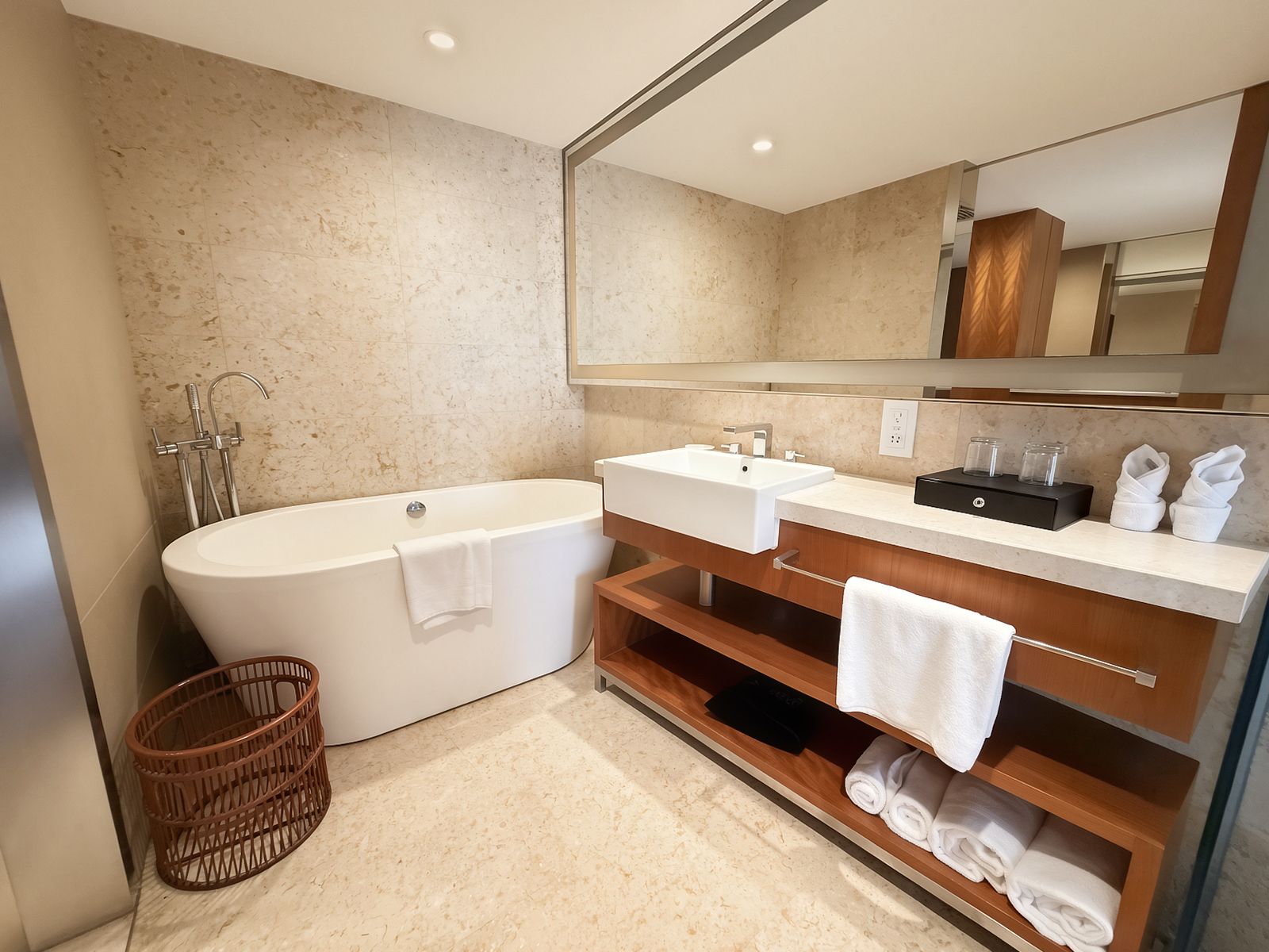 A modern bathroom with a freestanding bathtub, a vanity with a mirror, and a built-in shelf for towels.