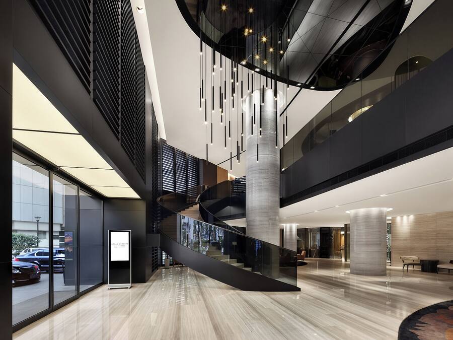 A modern interior with a central spiral staircase, glass railings, and a polished floor.