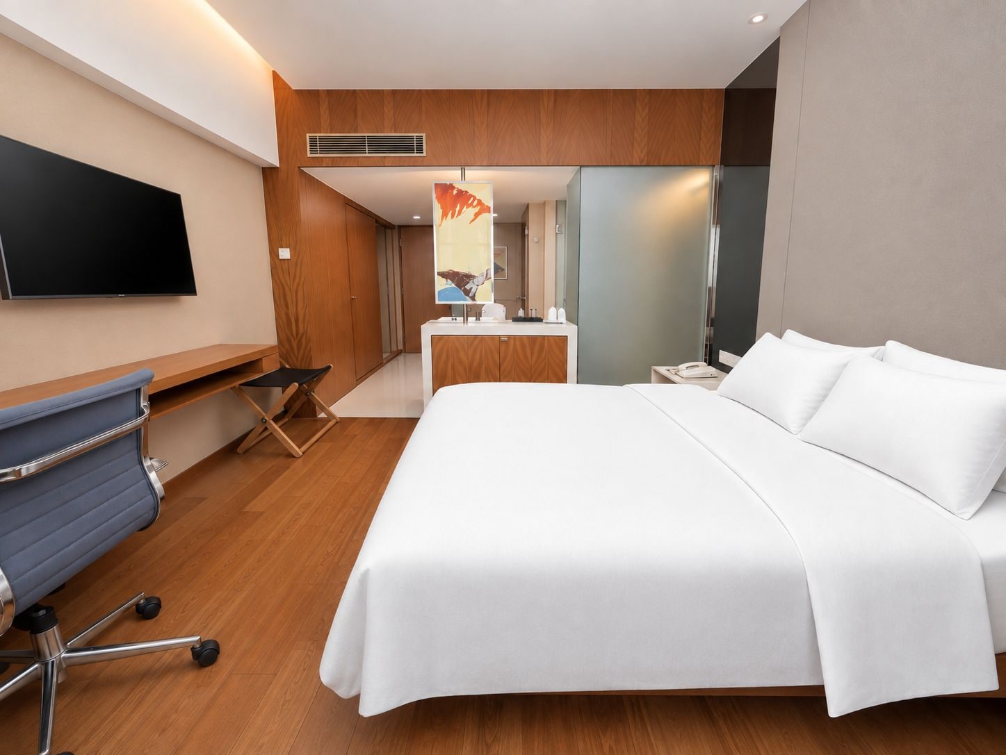 Una habitación de hotel con cama, escritorio, silla, televisión y baño.