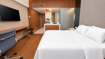 Una habitación de hotel con cama, escritorio, silla, televisión y baño.