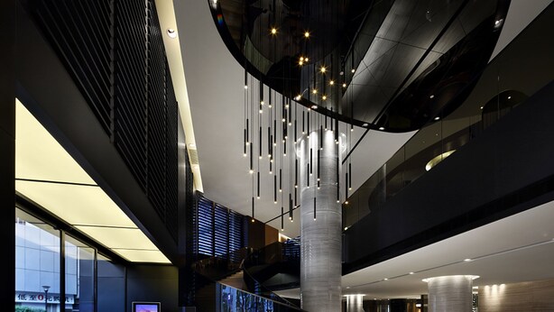 Un intérieur moderne avec une façade en verre, un escalier et une colonne centrale.