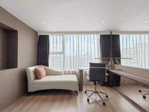 Een moderne hotelkamer met een bank, een bureau en uitzicht op de stad.