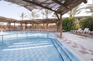 Piscina com espreguiçadeiras e área coberta.