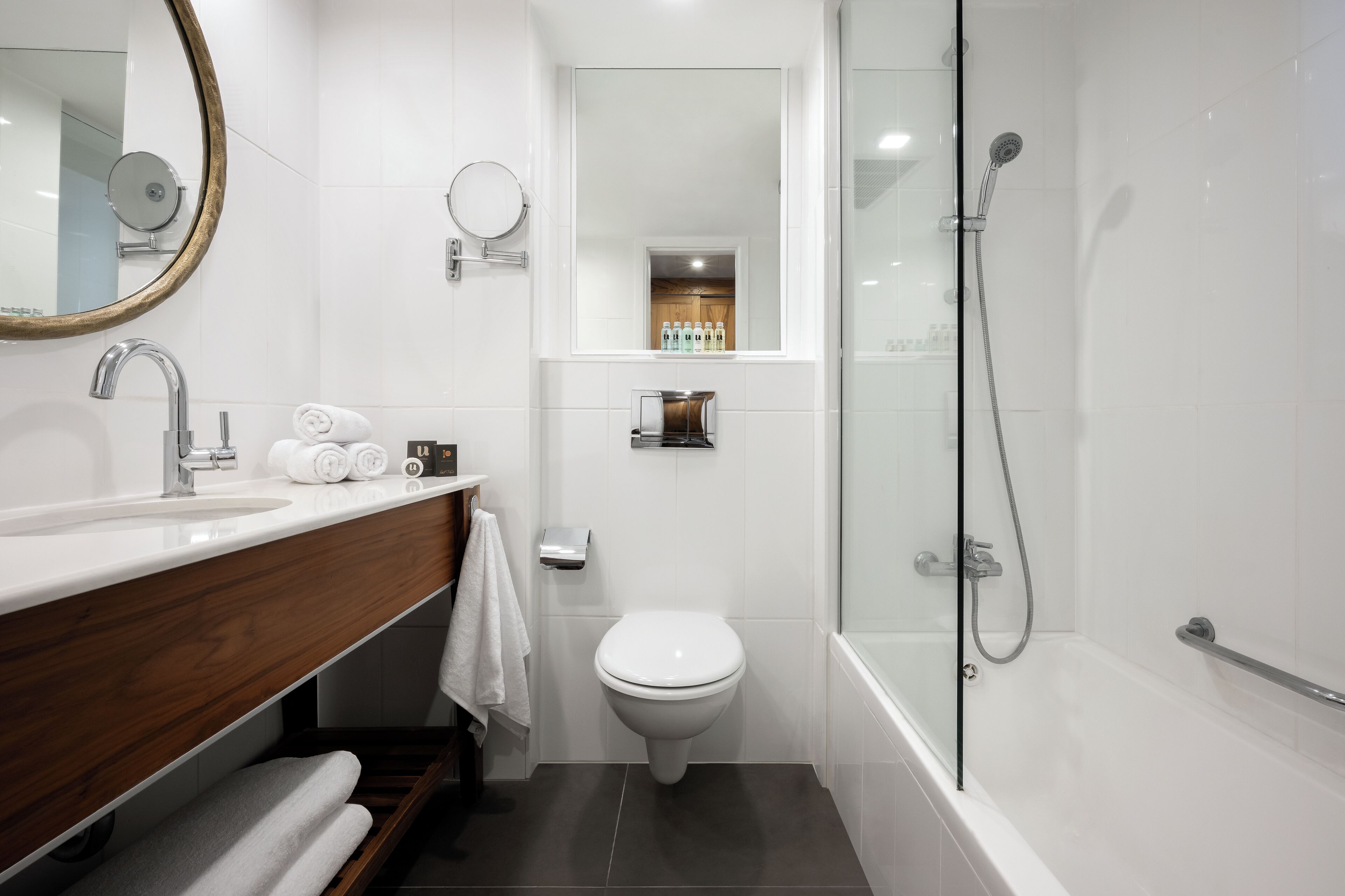 A modern bathroom with a white sink, a toilet, and a glass-enclosed shower area.