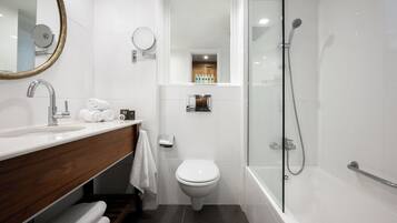 A modern bathroom with a white sink, a toilet, and a glass-enclosed shower area.