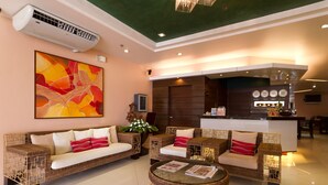 A modern hotel lobby with wicker furniture, a glass coffee table, and a large abstract painting. - Allure Hotel & Suites (Mandaue)