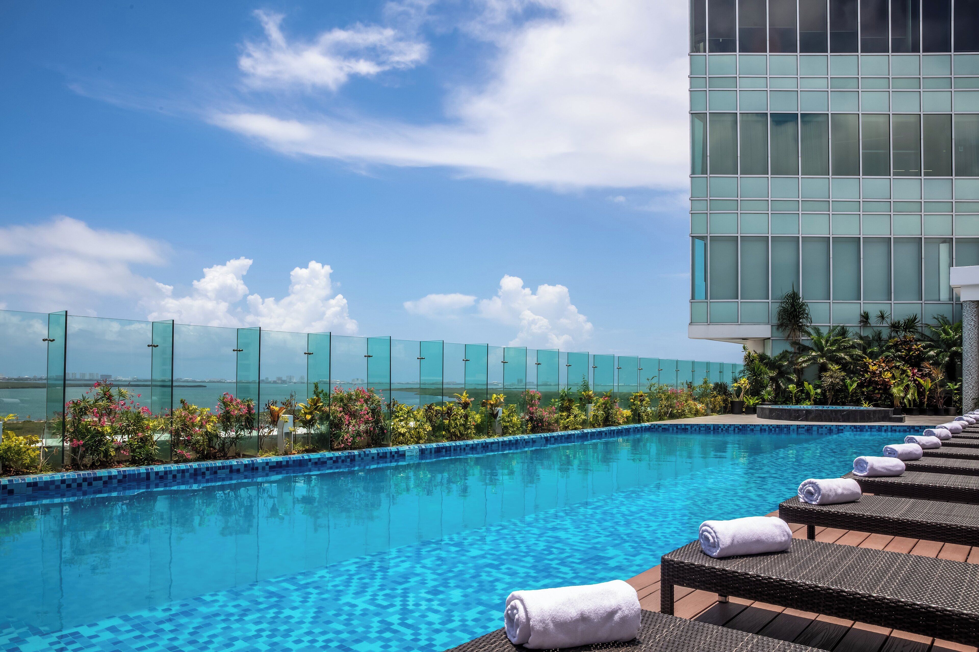 A swimming pool with lounge chairs and a glass fence.
