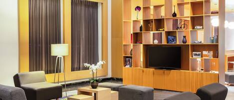 A modern living room with a sofa set, a coffee table, a TV, and a bookshelf with various items.