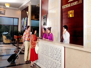 A reception area with a reception desk, a large window, and a sign for VietStar Resort & Spa. - VietStar Resort & Spa (Binh Kien)