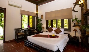 A spacious bedroom with a large bed, a sitting area with a table and chairs, and multiple windows providing natural light. - VietStar Resort & Spa (Binh Kien)