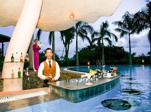 A poolside bar area with a bartender, a woman in a purple dress, and a tropical setting with palm trees. - VietStar Resort & Spa (Binh Kien)