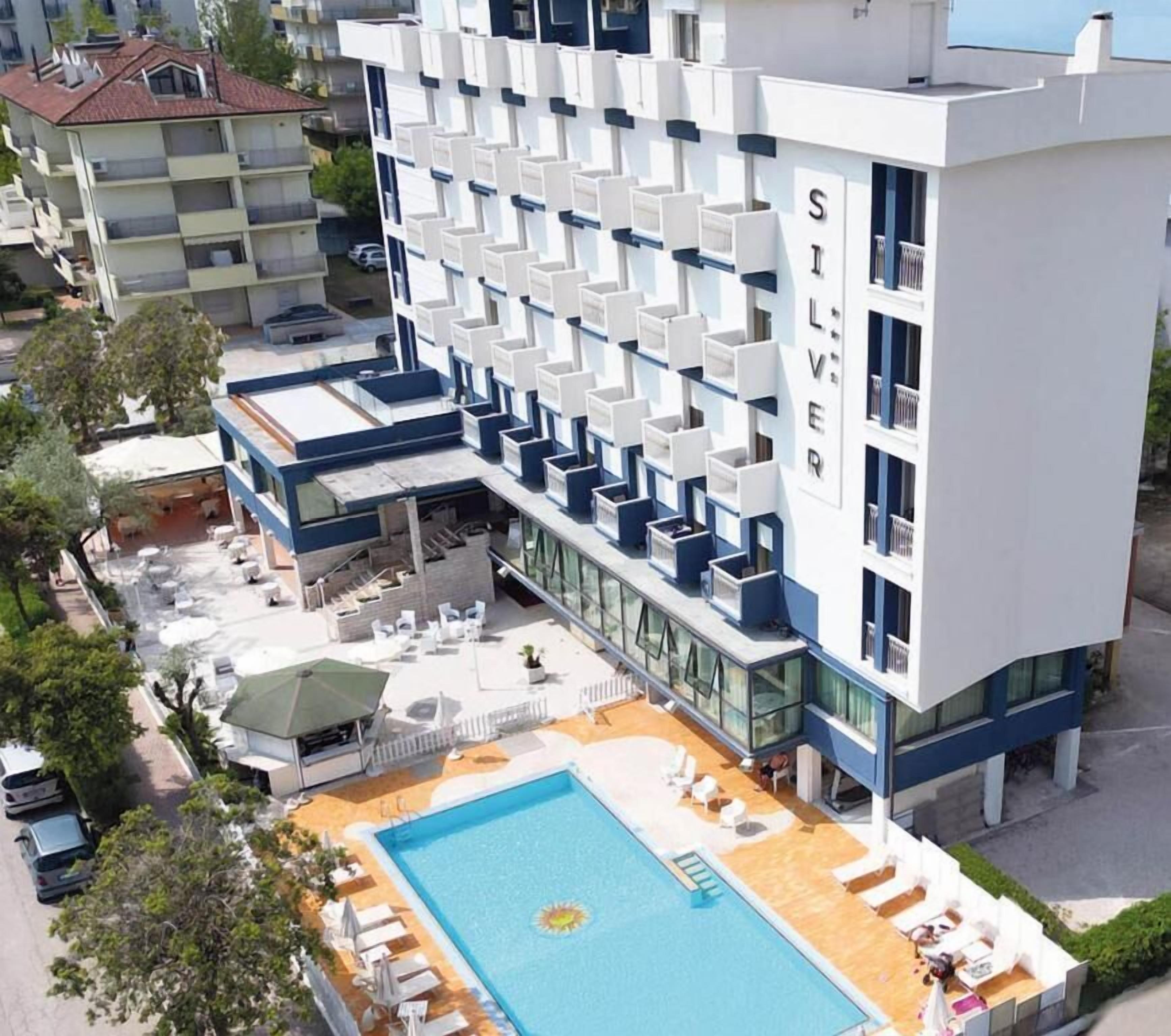 Un hotel con piscina, area salotto all'aperto e balconi.