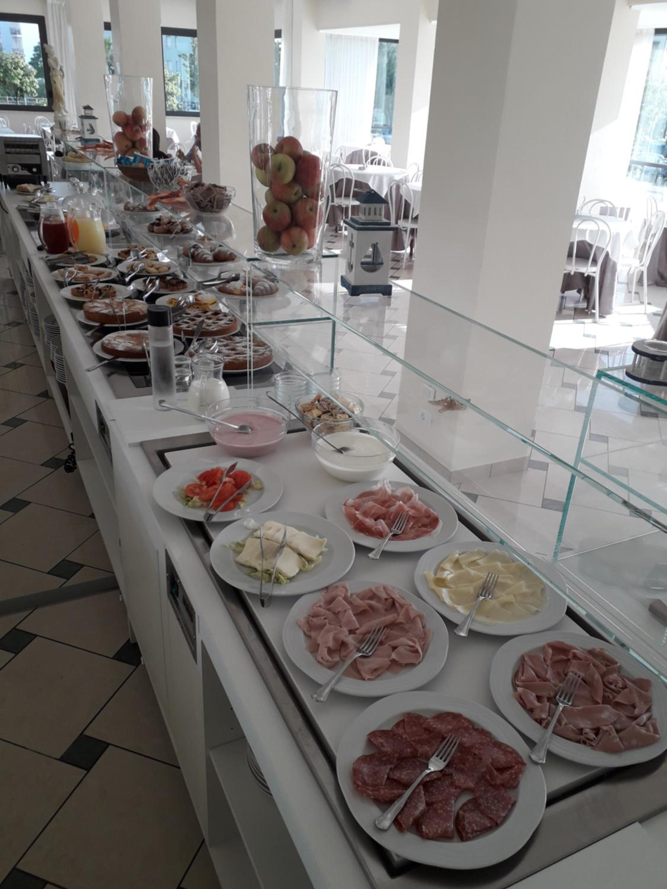 Un bufé con diversos alimentos, incluyendo carnes, quesos y frutas.