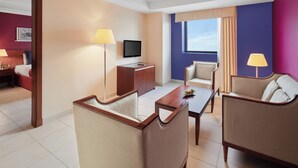 A hotel room with a bed, a desk, a TV, two armchairs, a coffee table, and a window with curtains. - Makarem Al Bait Hotel (Makkah)
