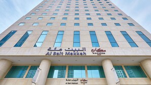 A tall building with a modern architectural design, featuring a prominent sign that reads "Al Bait Makkah" and "Makarem" in Arabic. - Makarem Al Bait Hotel (Makkah)