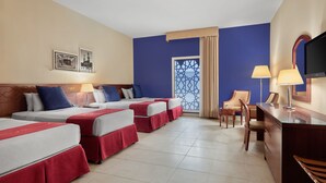 A hotel room with four beds, a desk, a chair, a TV, and a decorative window. - Makarem Al Bait Hotel (Makkah)