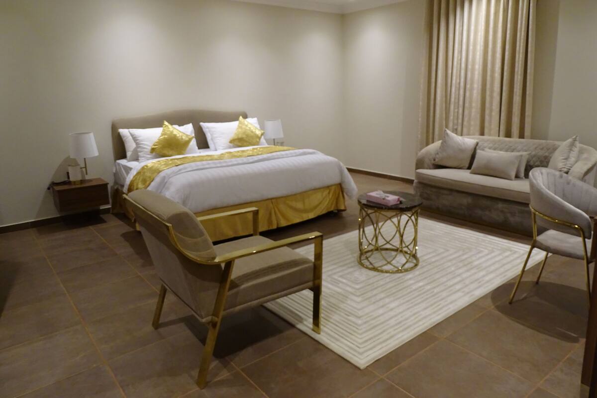 A modern bedroom with a large bed, a sofa, a chair, and a small table.