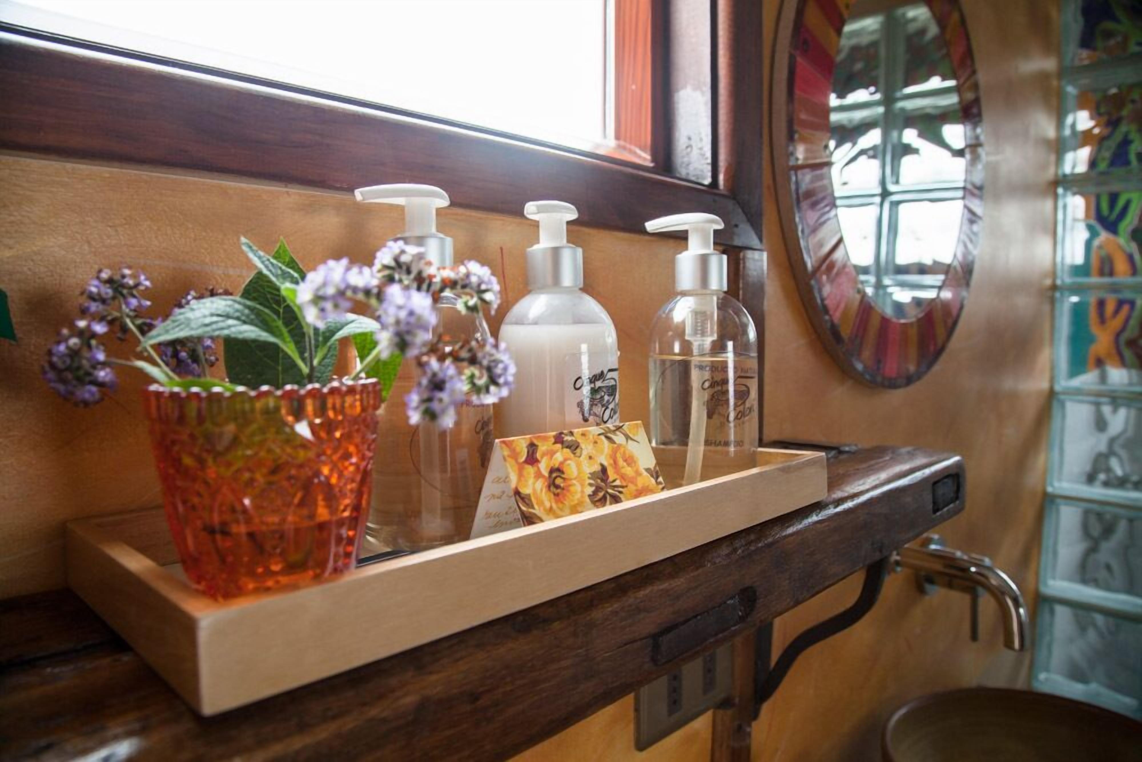 A bathroom vanity with a wooden countertop, a mirror, and a shelf with toiletries.
