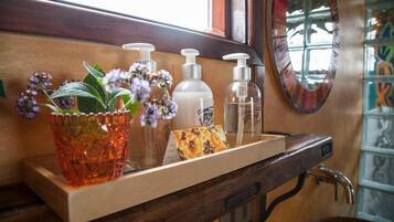 A bathroom vanity with a wooden countertop, a mirror, and a shelf with toiletries.