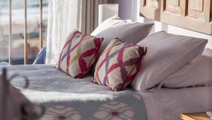 A bedroom with a bed, pillows, a nightstand, and a view of the sea. - Cinque Colori (Algarrobo)