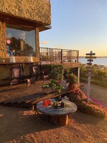 Una terraza de madera con asientos al aire libre, una mesa con bebidas y un cartel con indicaciones.
