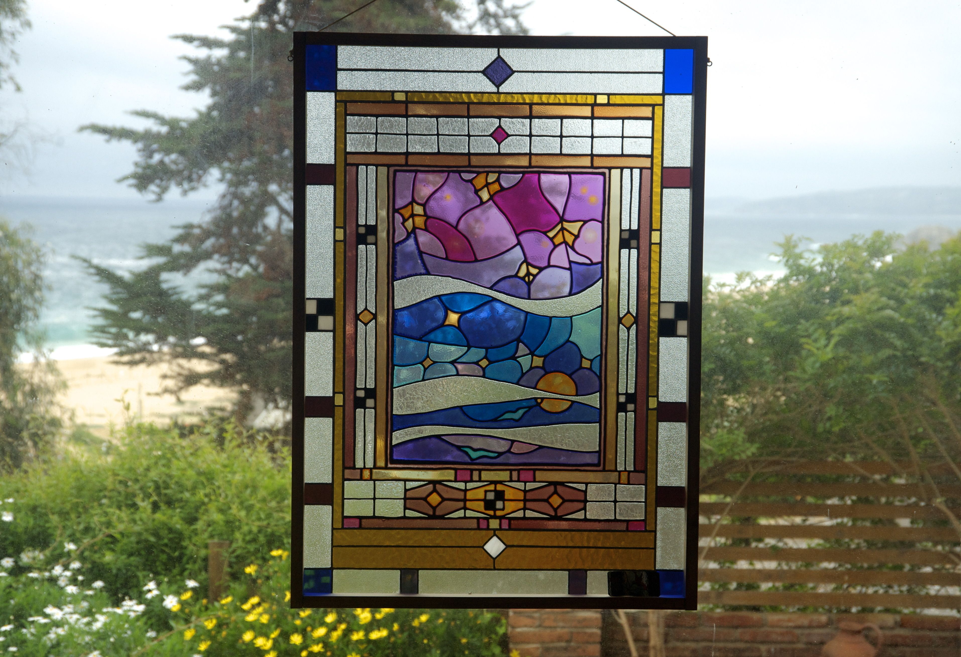 A stained glass window with a beach and ocean view.
