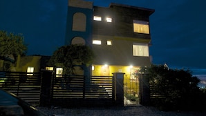 A multi-story building with a prominent tower, a gated entrance, and a well-lit facade. - Cinque Colori (Algarrobo)