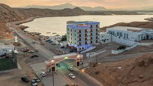Um hotel com vista para a água e montanhas ao fundo.