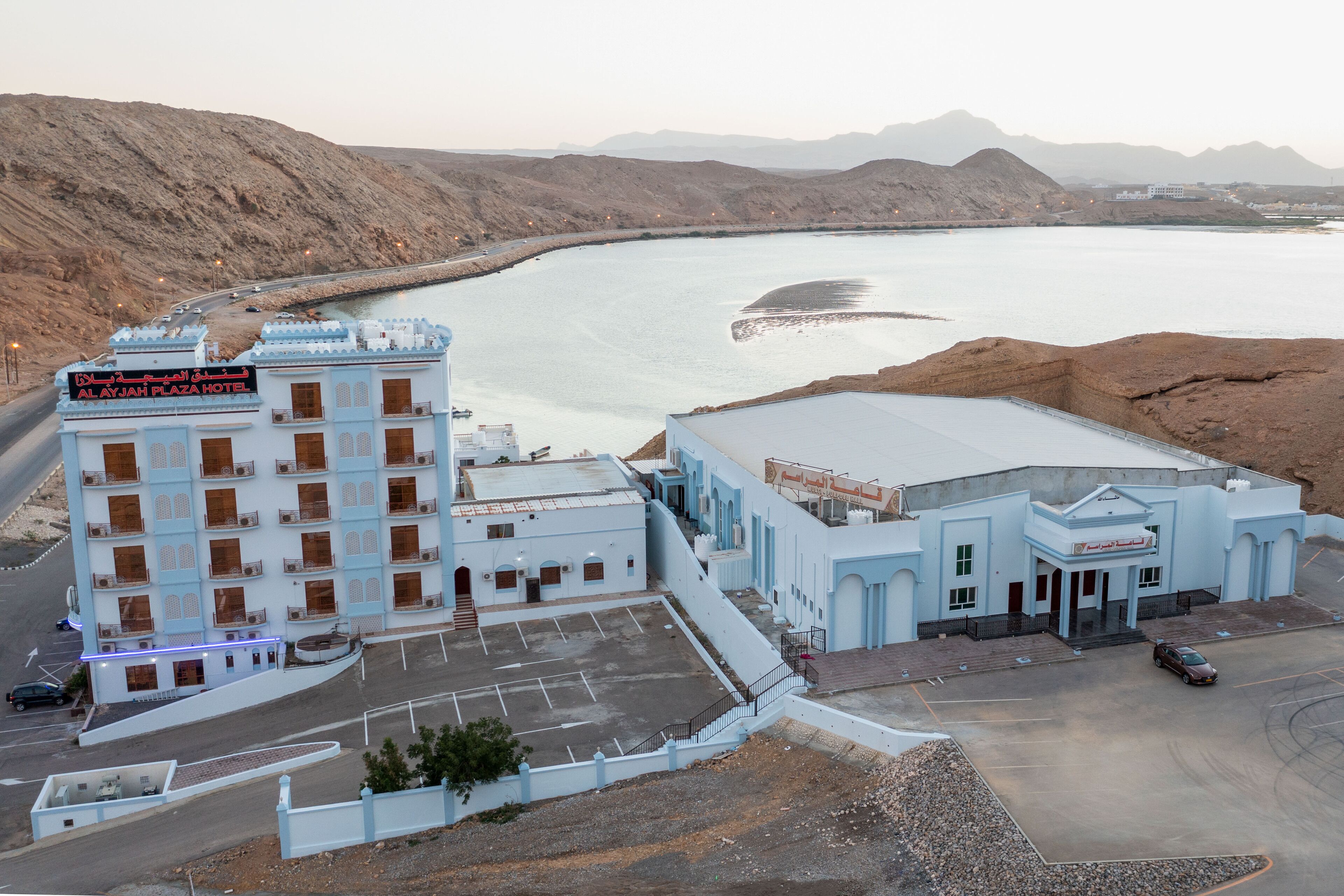 A hotel with a parking lot and a view of a large body of water.