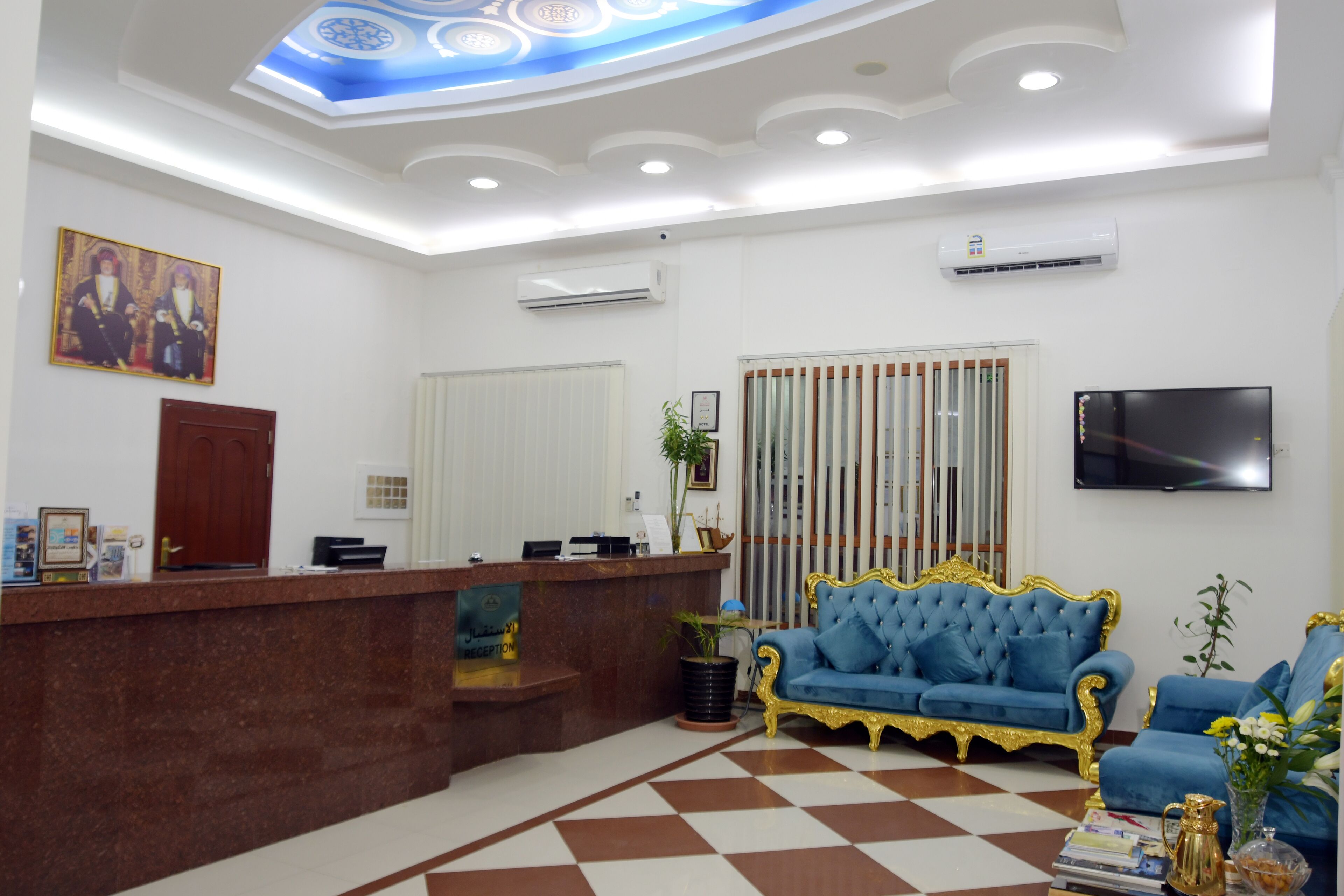 A reception area with a reception desk, a blue sofa, and a television on the wall.