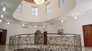 Um átrio amplo com teto alto, uma escadaria espiral central e um elegante guarda-corpo de ferro forjado.